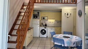 A compact kitchen with a washing machine, a microwave, and a dining area with a table and chairs. - Condominium with swimming pool and secure gated parking. (Saint palais sur mer)