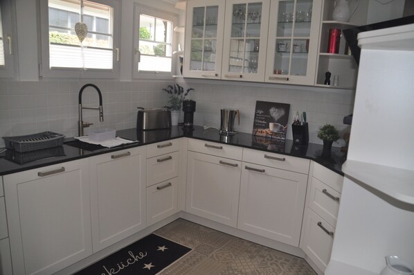A kitchen with white cabinets, a black countertop, and a refrigerator.