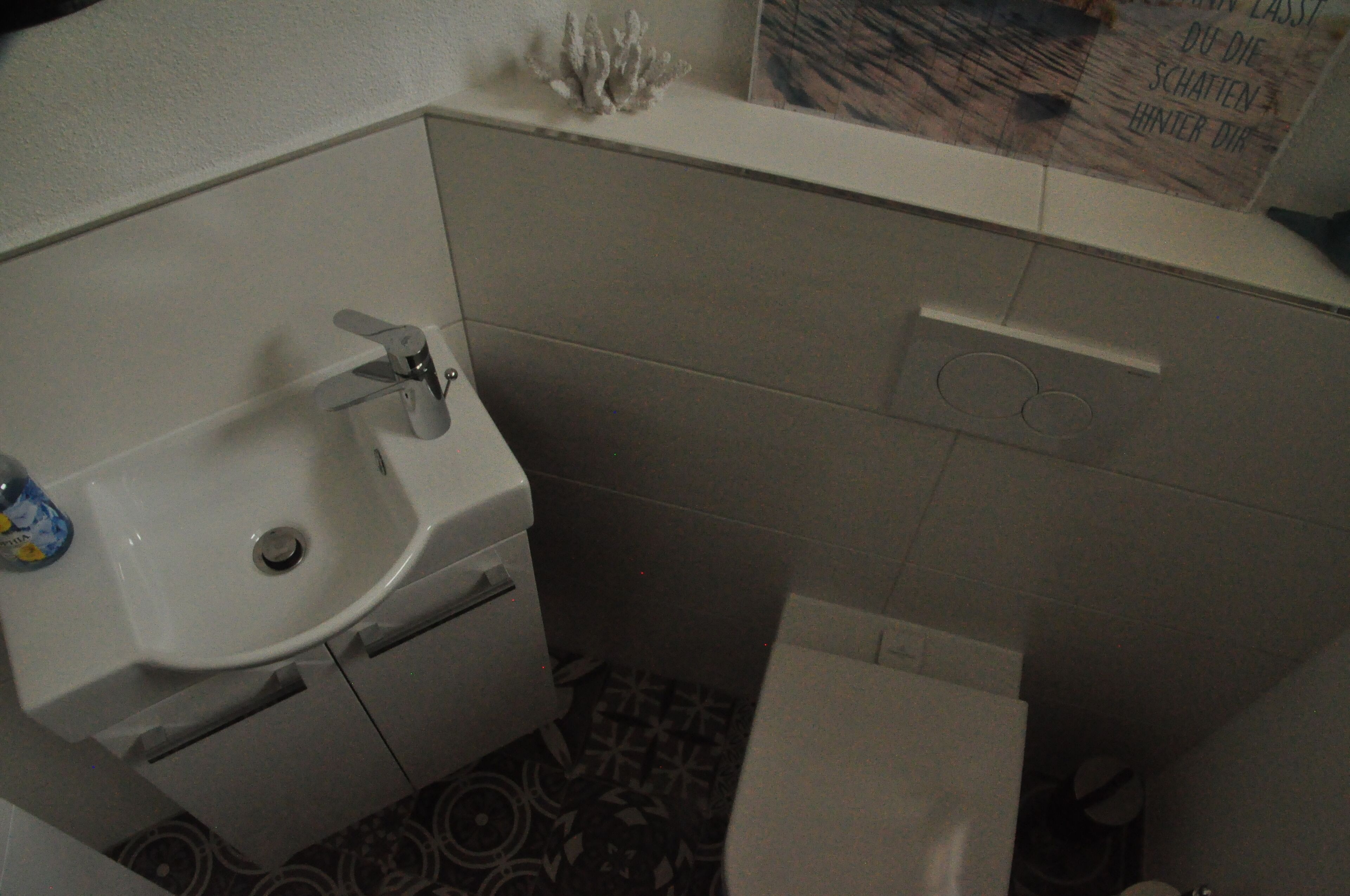 Et lille badeværelse med en hvid vask, toilet og bruseområde.