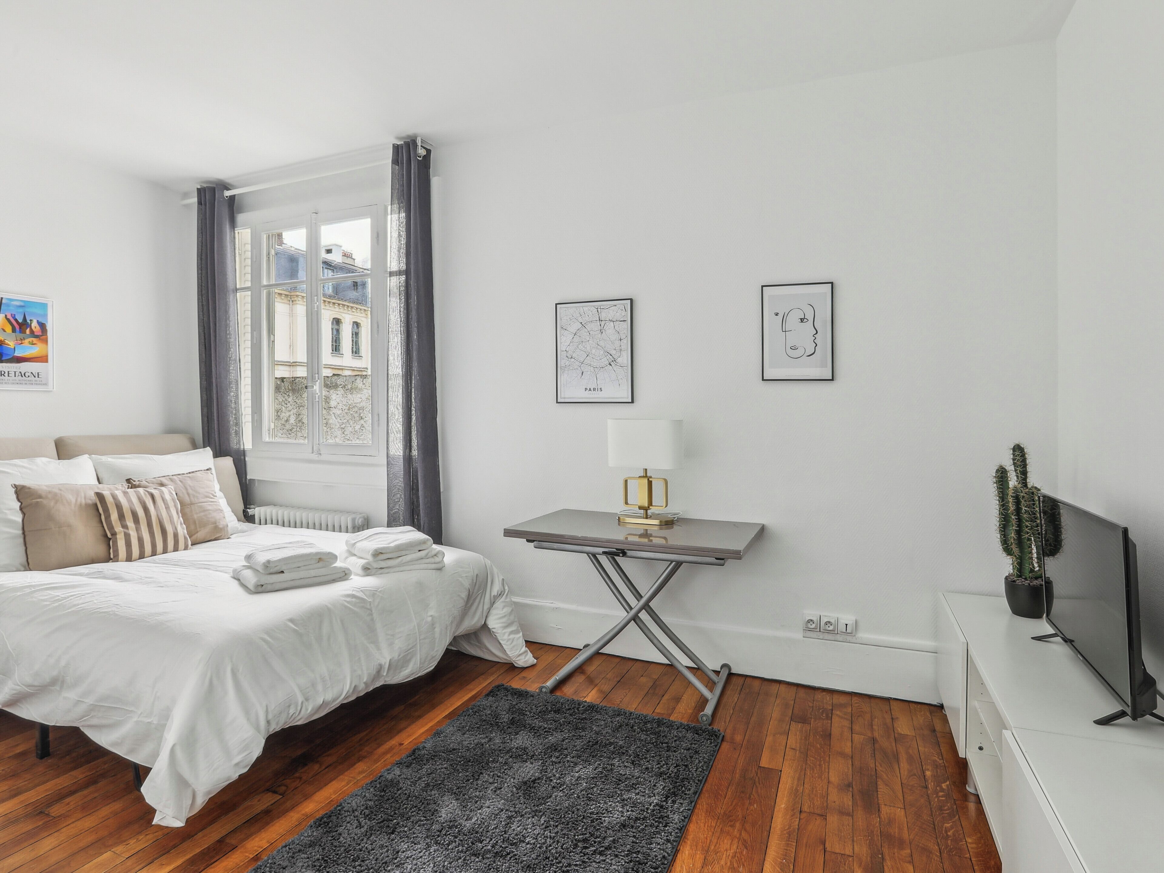 A modern bedroom with a bed, bedside table, and a window with curtains.