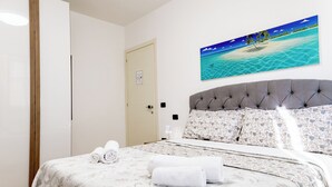 Una camera d'albergo con un letto, un quadro raffigurante una spiaggia e una porta.
