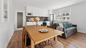A modern apartment with a wooden dining table, a grey sofa, and a kitchen area. - GuestReady - Lovely family home in Boavista (Boavista)