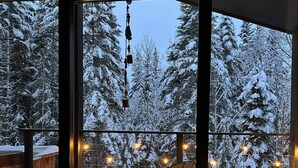 A wooden deck with a table and chairs, overlooking a snowy forest. - Hôtel à la maison - Villa le Pôle Nord (La Malbaie)