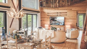 A spacious living room with a large window, a mounted kayak, and a painting on the wall. - Hôtel à la maison - Villa le Pôle Nord (La Malbaie)