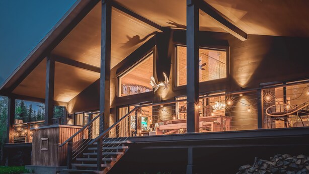 A modern wooden house with a covered porch, large windows, and a staircase leading to the upper floor. - Hôtel à la maison - Villa le Pôle Nord (La Malbaie)