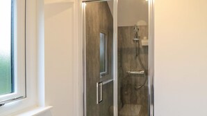 Un baño moderno con cabina de ducha de vidrio, inodoro a la vista y ventana.