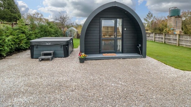 Una estructura acogedora de color oscuro, con arco y un pequeño porche, además de un jacuzzi.