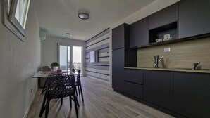 Eine moderne Küche mit dunklen Schränken, einer Holzarbeitsplatte und einem Essbereich mit einem Glastisch und Stühlen.