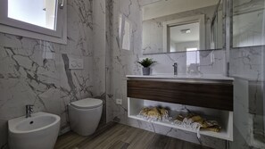 A modern bathroom with a marble backsplash, a wooden vanity, a bidet, and a mirror.