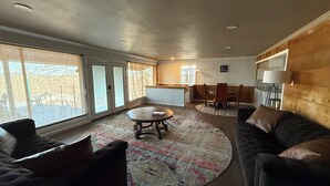 A spacious living room with a round coffee table, a dark leather sofa, and a dining area with wooden chairs and a table. - Lake Front House with Private Dock and boat rental available!  Lake Eufala (Checotah)
