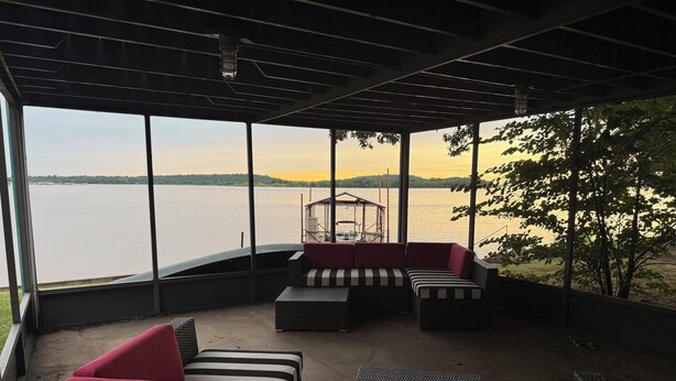 A covered outdoor seating area with a view of a lake and distant hills. - Lake Front House with Private Dock and boat rental available!  Lake Eufala (Checotah)