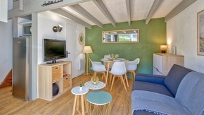 Un espacio habitable compacto con kitchenette, sofá, zona de comedor con sillas y televisión.