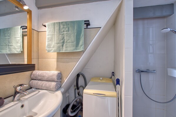 Un baño con lavamanos, espejo, toallas y ducha.