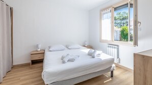 A minimalist bedroom with a large bed, bedside tables, a window with a view, and a hanging light fixture.
