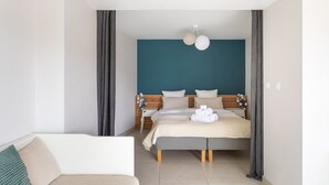Una habitación de hotel moderna con una cama, una mesita de noche, una silla y un gran ventanal con cortinas.
