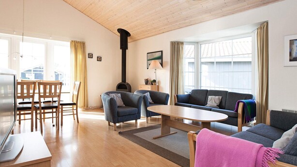 A spacious living area with a wooden ceiling, a fireplace, a sofa, a coffee table, and a TV. - 6 Person Holiday Home on a Holiday Park in Grasten (Grasten)