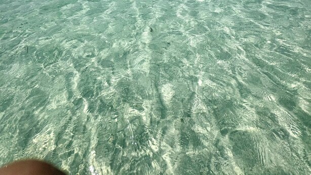 Une vue dégagée sur une plage, avec une eau turquoise peu profonde et un horizon lointain.