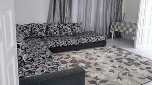 Un salon moderne avec un canapé, un tapis à motifs et des rideaux.
