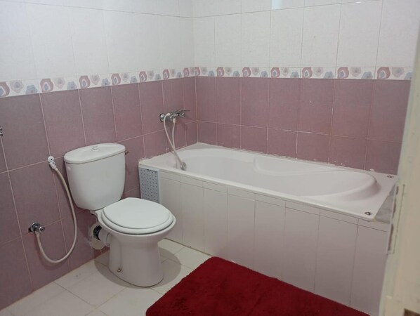 Une salle de bain comprenant des toilettes, une baignoire et une douche.