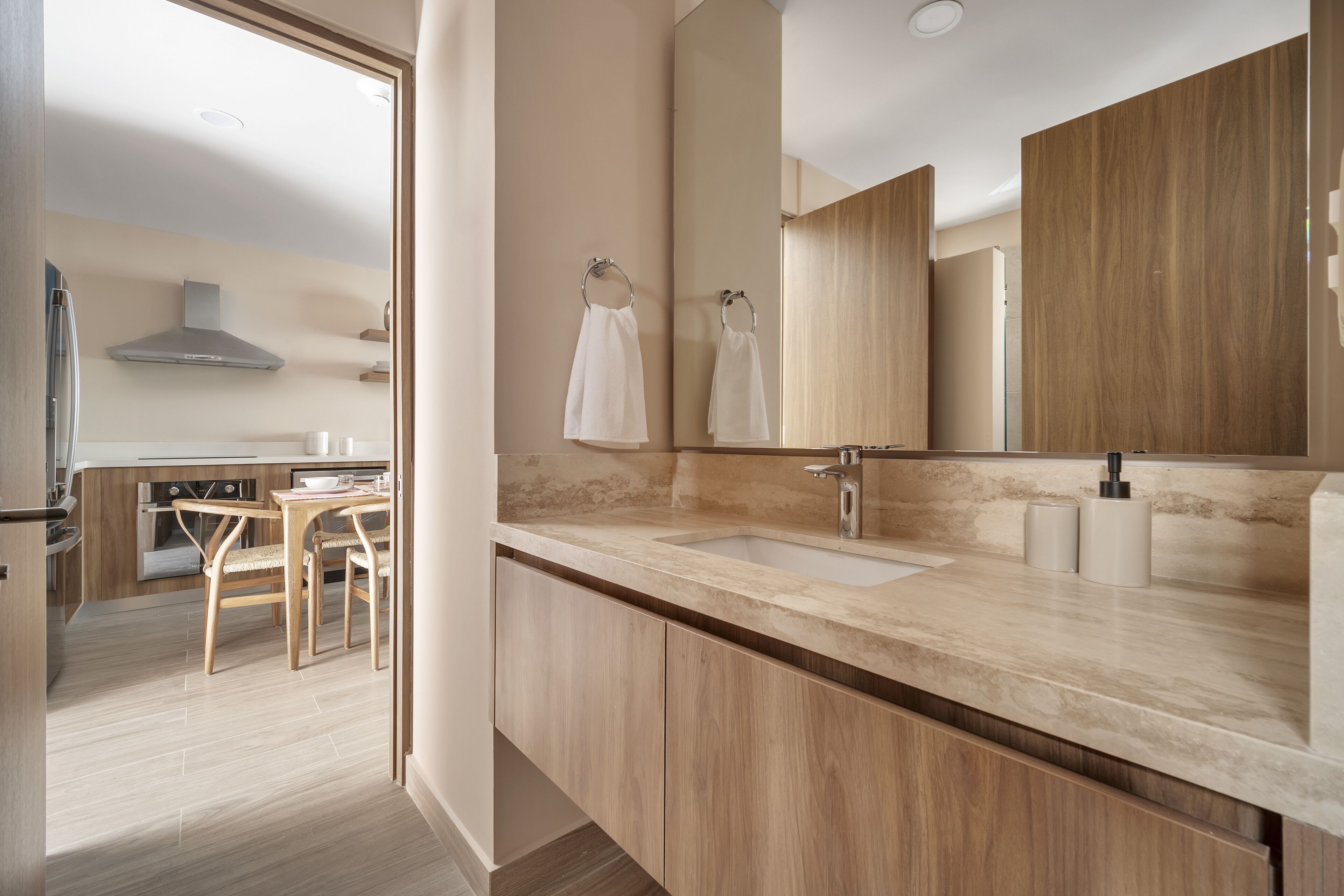 A modern bathroom with a large mirror, two sinks, wooden cabinets, and a visible toilet.