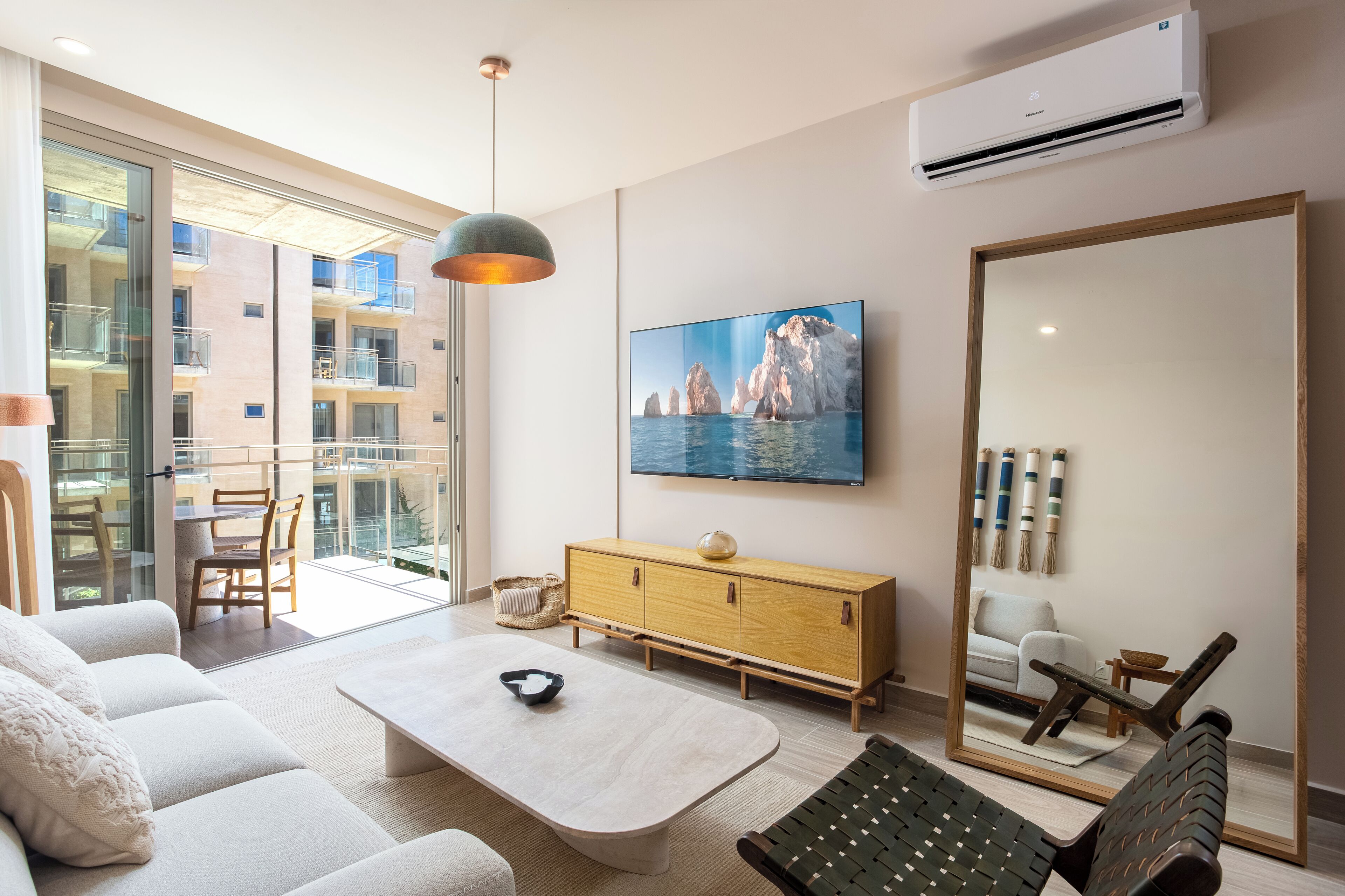 Una sala de estar moderna con un sofá, una mesa de centro y un espejo grande que refleja la habitación.