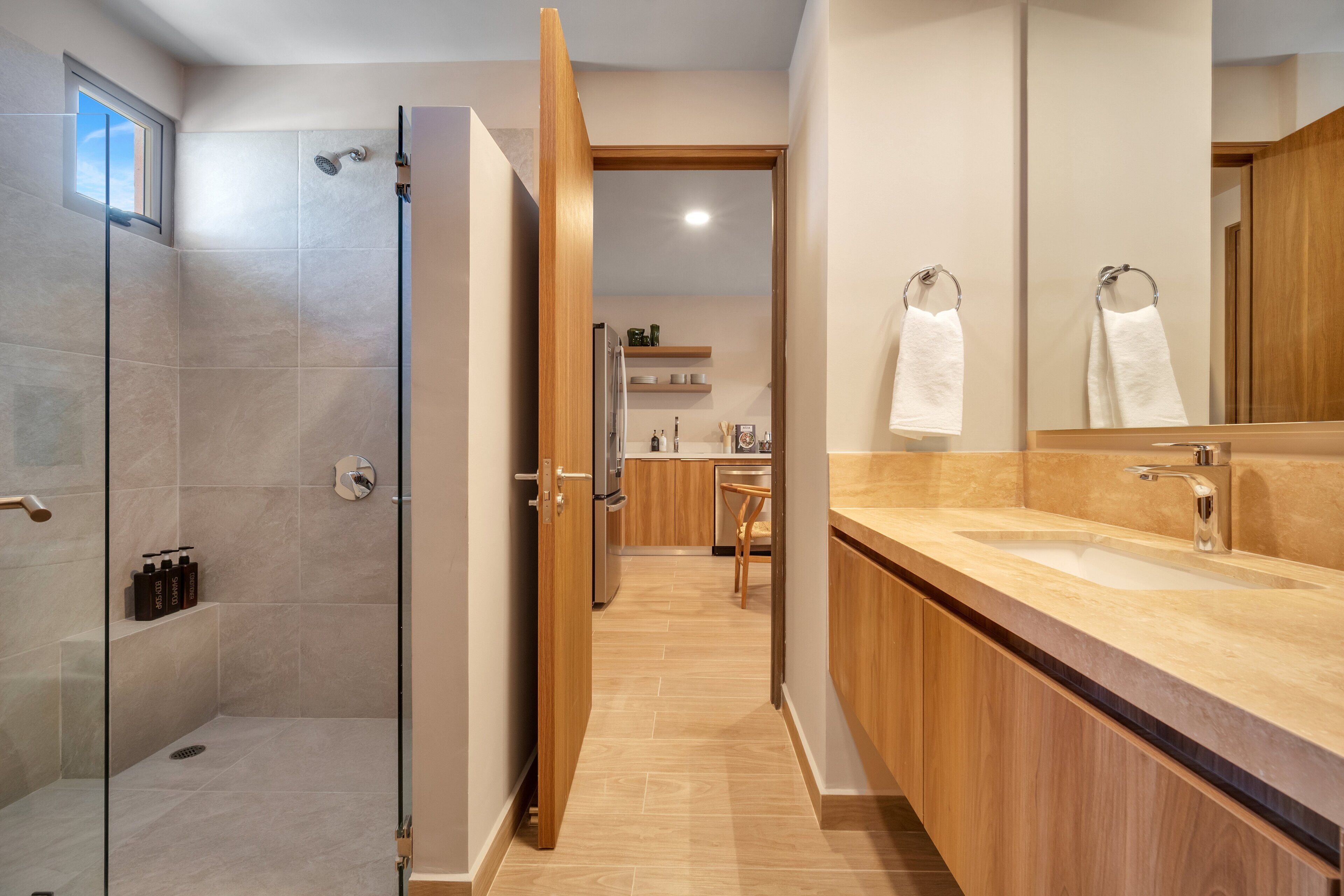 Een moderne badkamer met een douche, wastafel en spiegel.