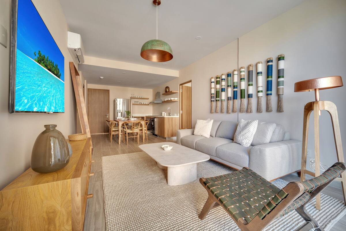 A modern living room with a sofa, coffee table, and a view of the kitchen.