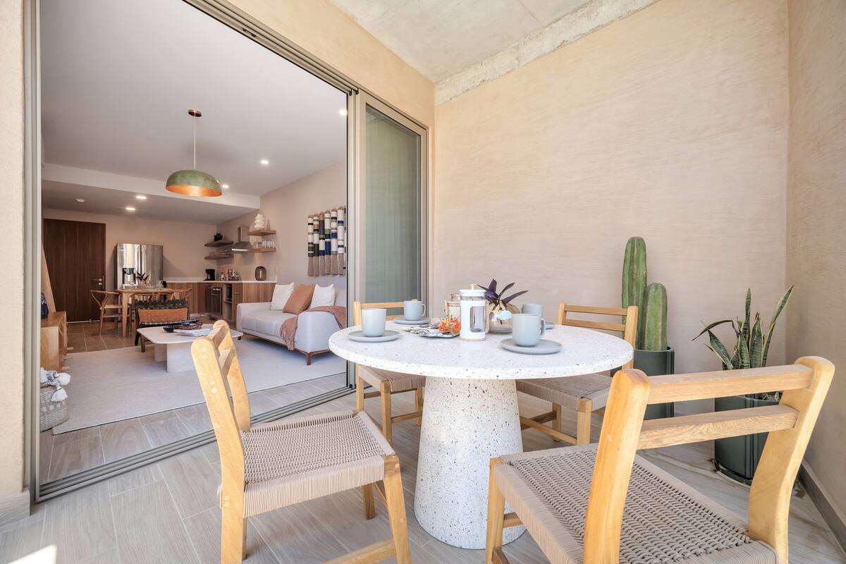 A modern living room with a round table, wooden chairs, and a sofa.