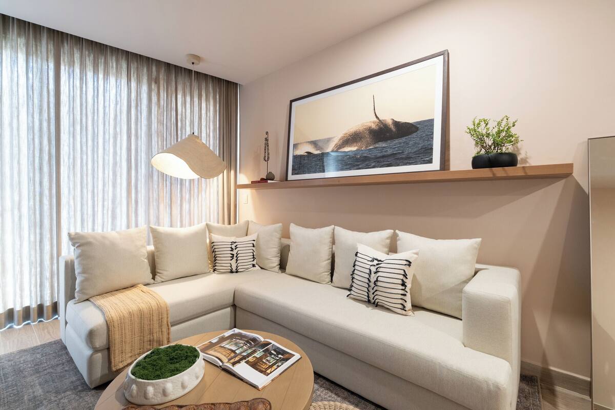 A modern living room with a sectional sofa, a coffee table, a framed picture of a whale, and a potted plant.