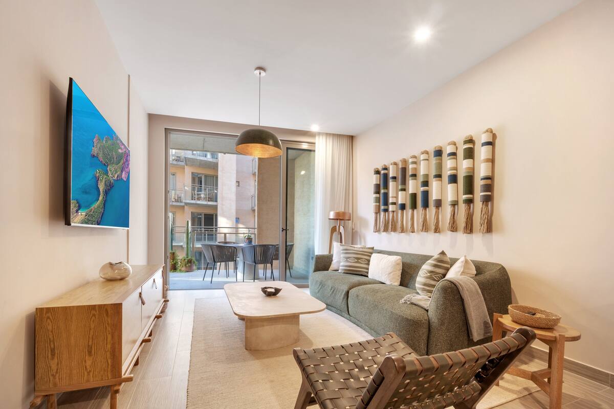 A modern living room with a sofa, coffee table, and a TV mounted on the wall.