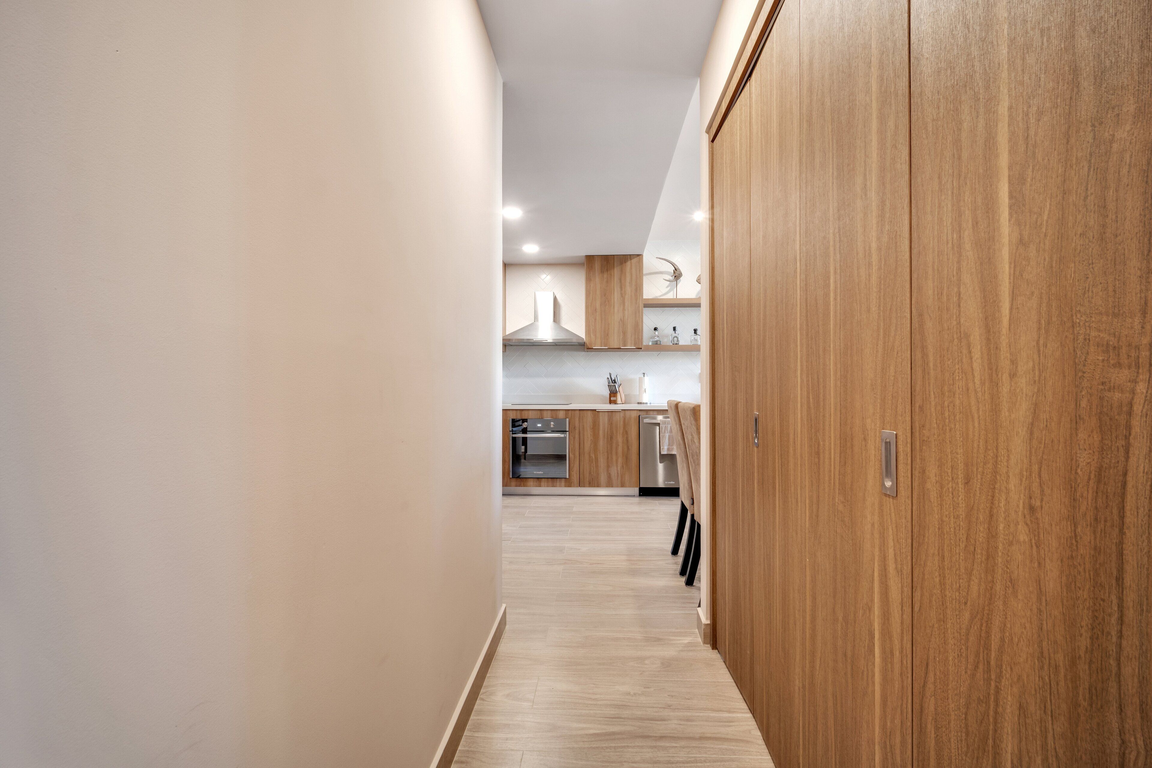 A modern kitchen with wooden cabinets, a stainless steel oven, and a light-colored floor.