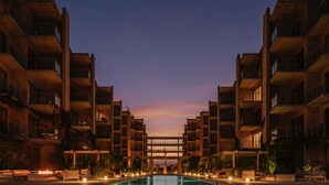 Un hôtel moderne doté d’une piscine centrale, de nombreux balcons et offrant une vue imprenable sur le coucher de soleil.
