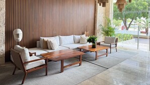 Un interior moderno con un panel de pared de listones de madera, un conjunto de sofás, una mesa de centro y lámparas colgantes.