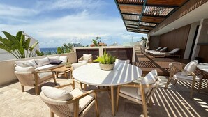 A rooftop terrace with outdoor seating, a round table, and a view of the city skyline.