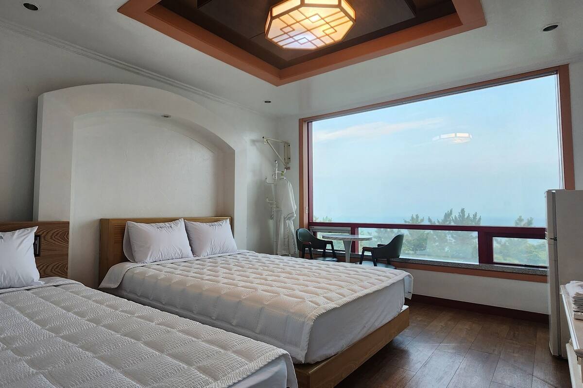 Ein Hotelzimmer mit zwei Betten, einem Balkon mit Tisch und Stühlen und einem großen Fenster mit Blick.