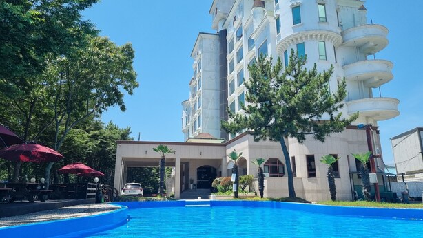 A large building with multiple floors and a swimming pool in front. - Namhae beach hotel (Namhae)
