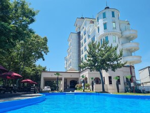 A large building with multiple floors and a swimming pool in front. - Namhae beach hotel (Namhae)