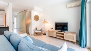 A modern living room with a sofa, TV, and a lamp.