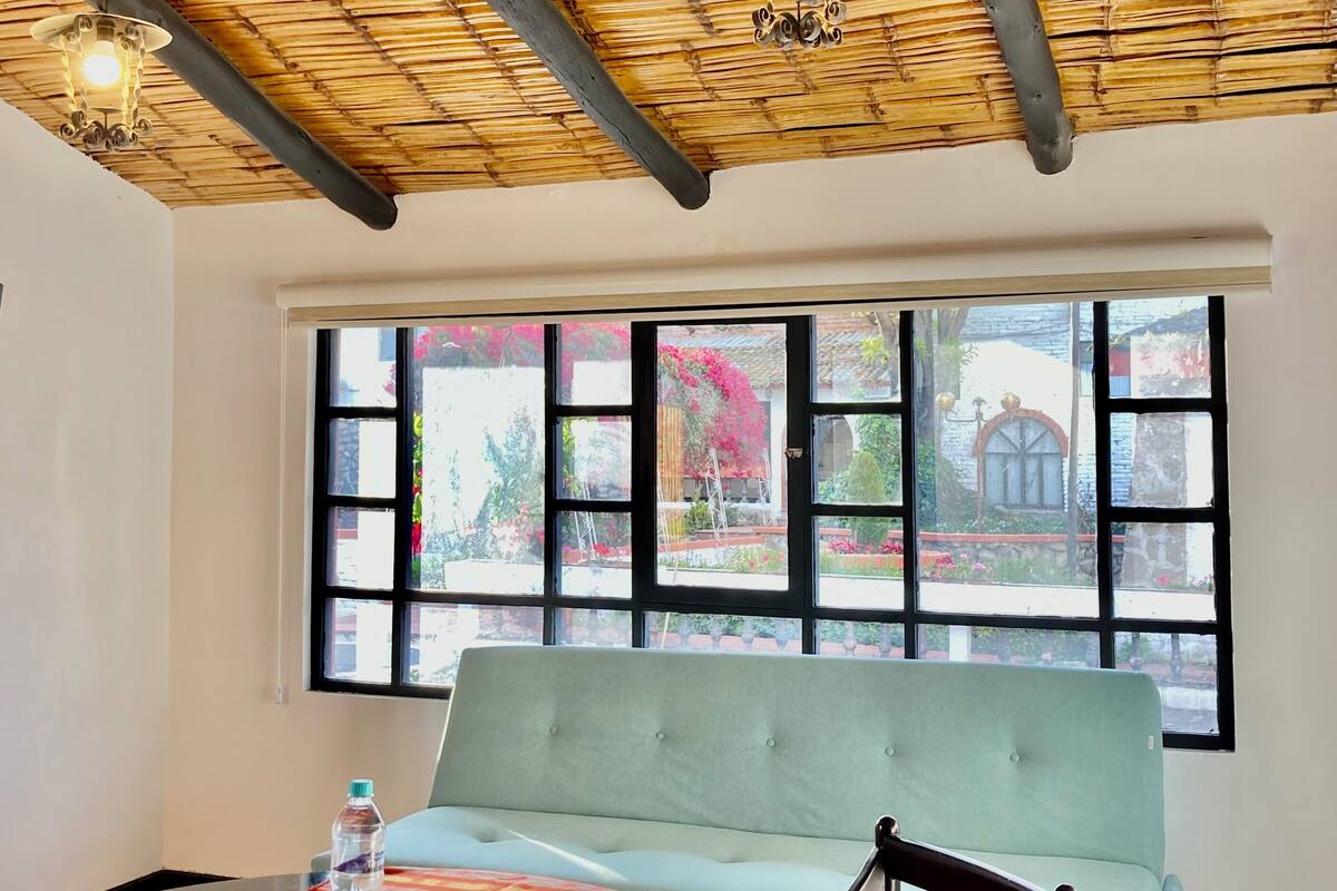 Ein Essbereich mit Tisch, Stühlen, einer Bank und einem großen Fenster mit Blick ins Freie.
