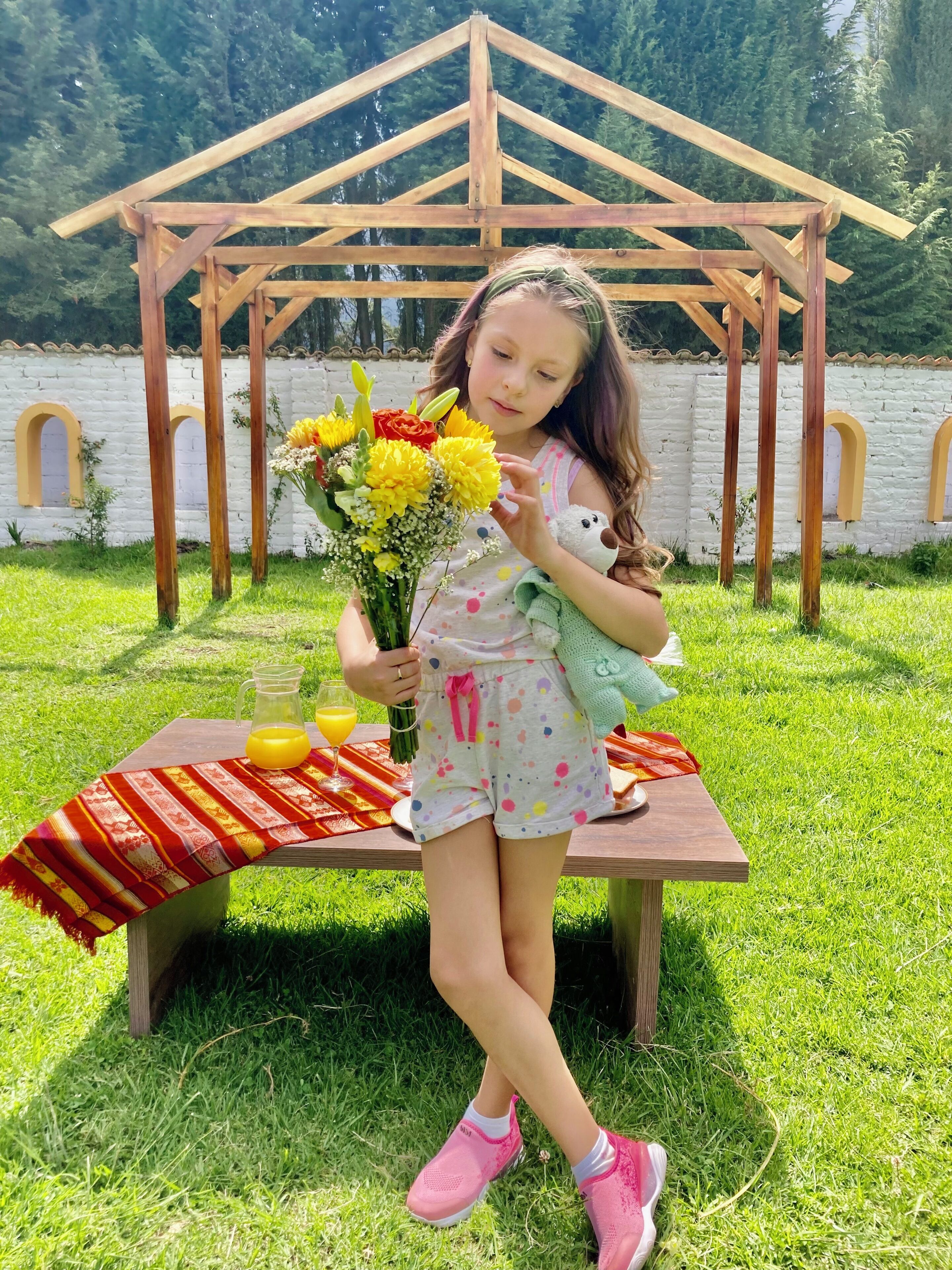 A wooden gazebo with a table set for a picnic.
