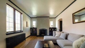 A living room with a fireplace, a sofa, a coffee table, and a radiator. - The Safe Harbor Home | Quiet Retreat, Fire Pit, Nature (Conestoga)