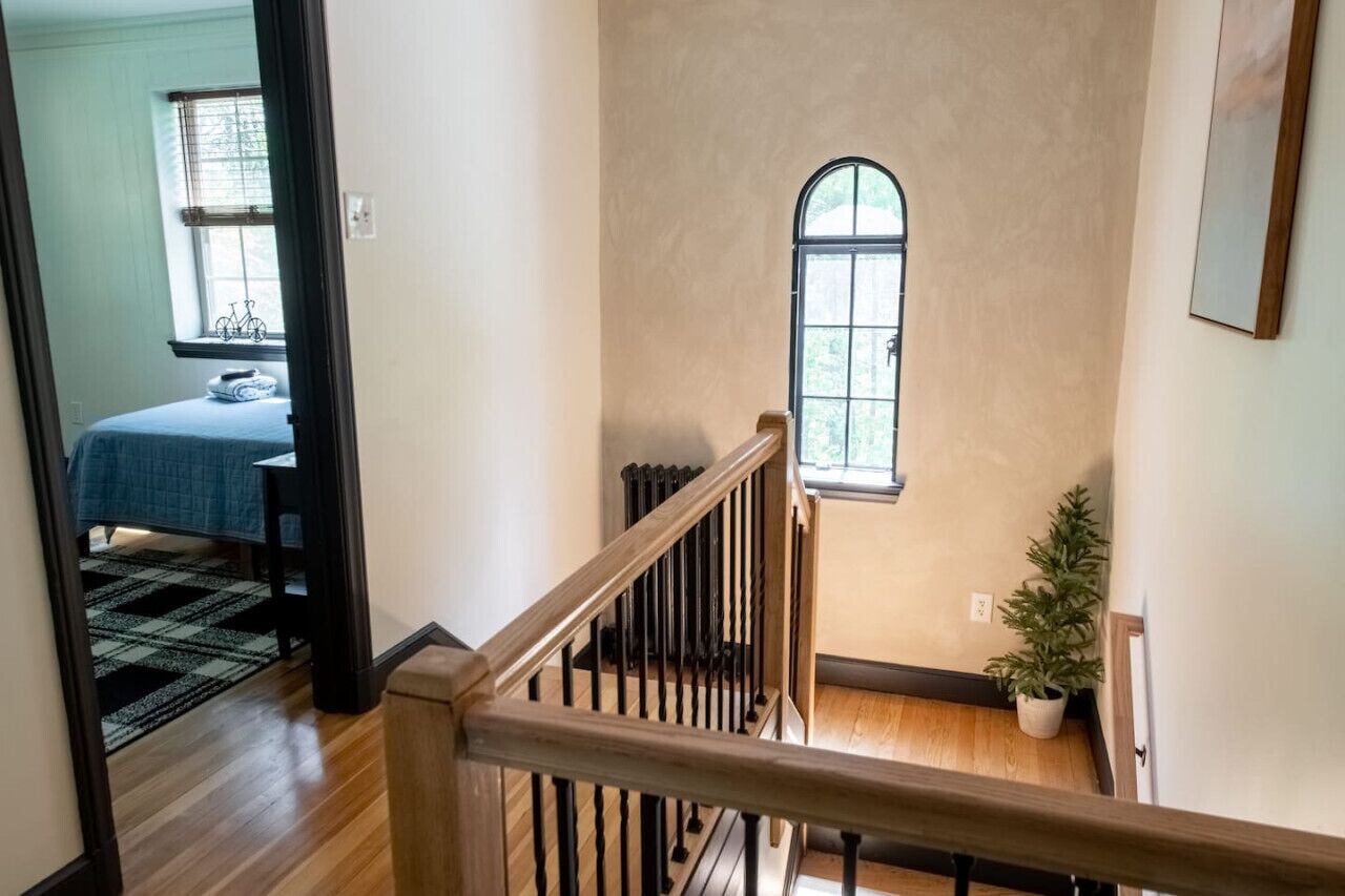Un escalier avec une rampe en bois et un radiateur fixé au mur.