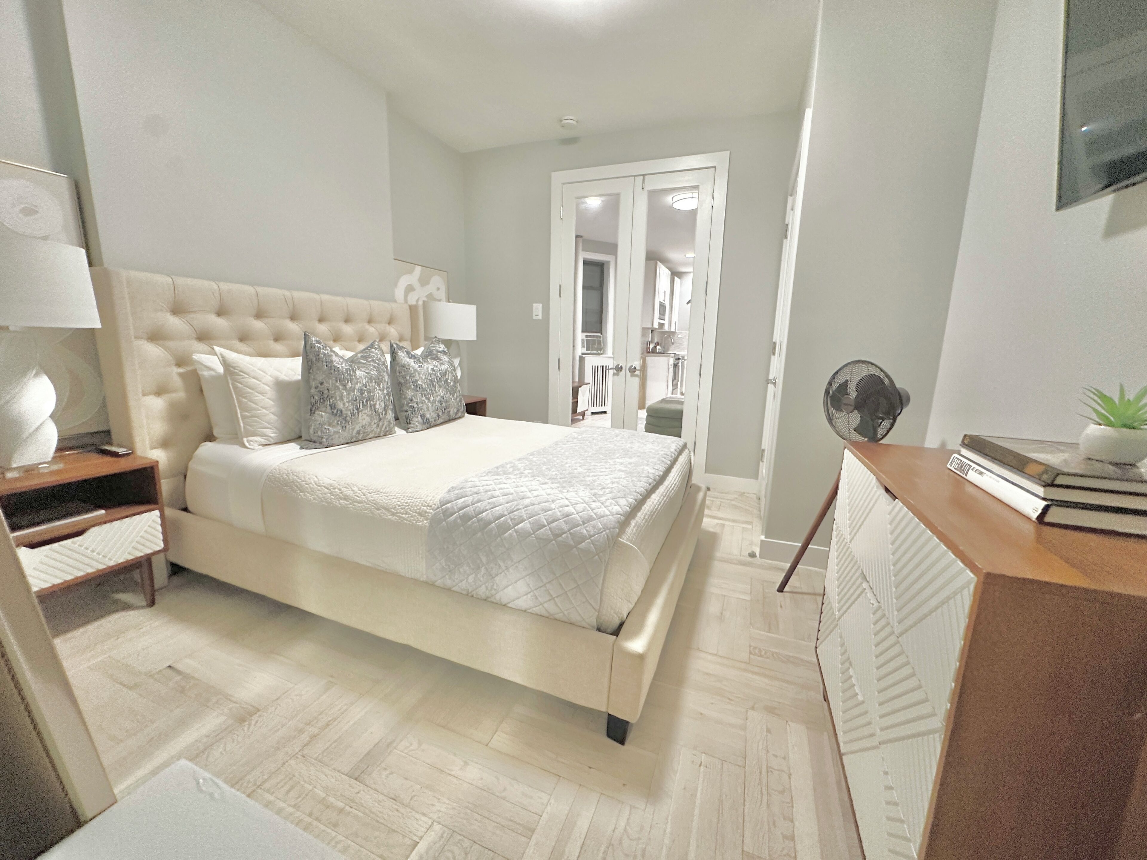 Een slaapkamer met een bed, nachtkastjes, een bureau en een spiegel.