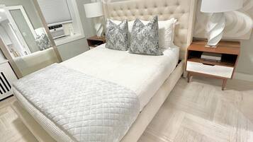 A bedroom with a large bed, two nightstands, a mirror, and a wall-mounted lamp.