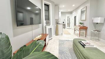 Una sala de estar moderna con un televisor de pantalla plana, un sofá, una mesa de centro y una planta verde grande.