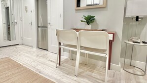 A modern kitchen with white cabinetry, a refrigerator, and a dining area with a table and chairs.