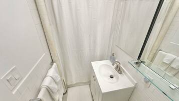 A modern bathroom with a white sink, glass shower enclosure, and a towel rack.