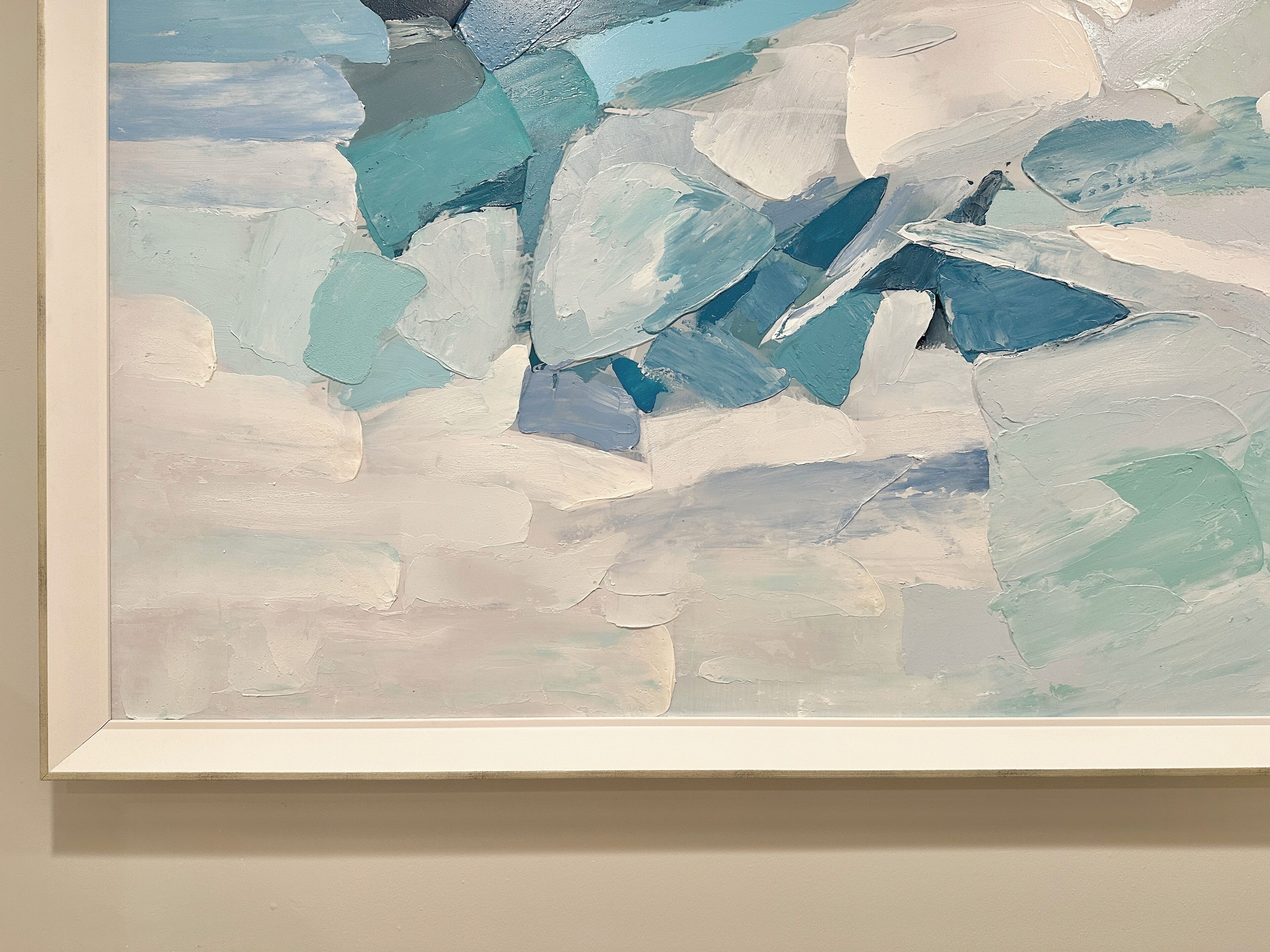 A framed abstract painting with a mix of blue and white colors.