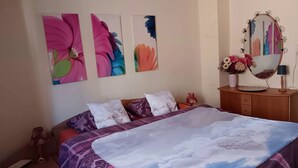 A bedroom with a bed, pillows, a dresser, a mirror, and wall art.
