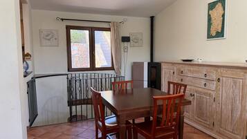 Un coin repas avec une table et des chaises en bois, une cuisine avec des placards en bois et une fenêtre avec des rideaux.